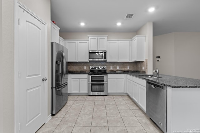 kitchen featuring sink, tasteful backsplash, kitchen peninsula, white cabinets, and appliances with stainless steel finishes