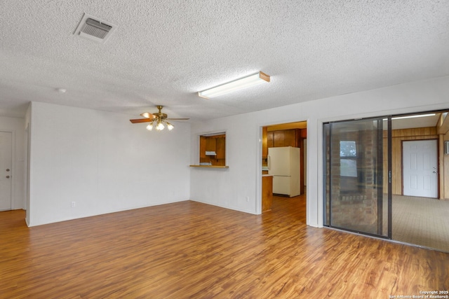 spare room featuring ceiling fan, light wood-type flooring, and a textured ceiling