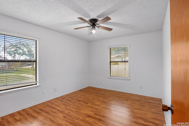 spare room with hardwood / wood-style flooring, ceiling fan, and a healthy amount of sunlight