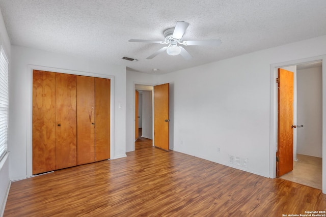 unfurnished bedroom featuring multiple windows, ceiling fan, a closet, and hardwood / wood-style flooring