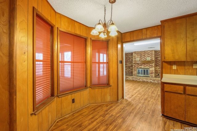 kitchen with decorative light fixtures, wood walls, a textured ceiling, and an inviting chandelier