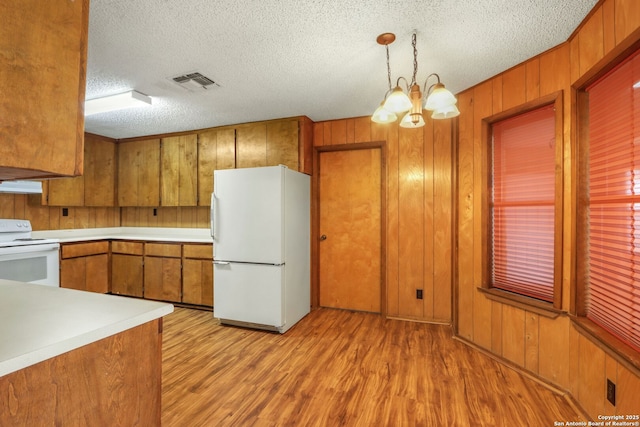 kitchen featuring stove, a textured ceiling, pendant lighting, white refrigerator, and an inviting chandelier