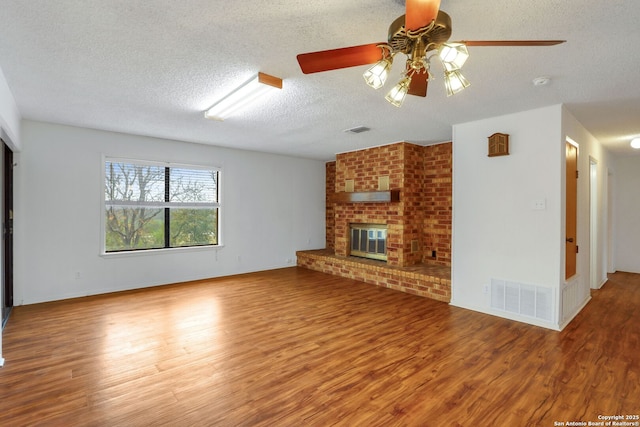 unfurnished living room featuring a fireplace, wood-type flooring, a textured ceiling, and ceiling fan