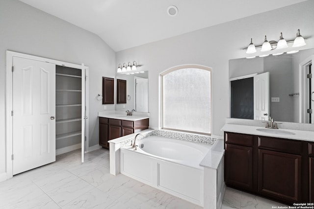 bathroom with a bathtub, vanity, and vaulted ceiling