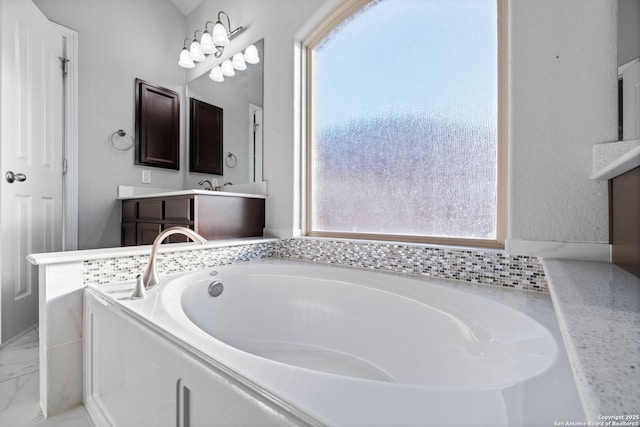 bathroom with plenty of natural light, a bath, and vanity