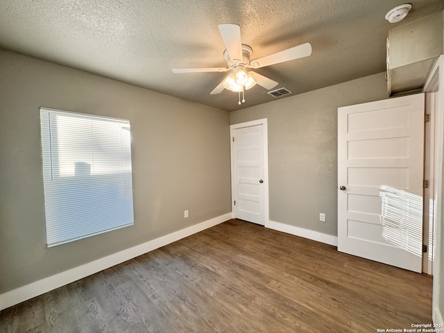 unfurnished bedroom featuring ceiling fan, dark hardwood / wood-style flooring, and a textured ceiling