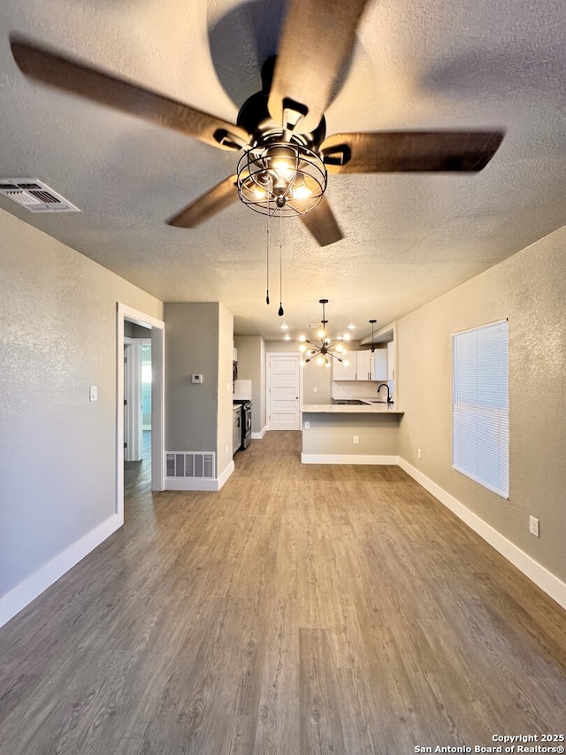 unfurnished living room featuring sink, a textured ceiling, and hardwood / wood-style flooring