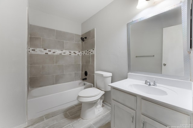 full bathroom featuring vanity, tiled shower / bath combo, and toilet