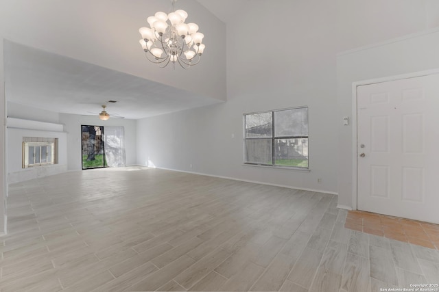 unfurnished living room featuring a tile fireplace and ceiling fan with notable chandelier