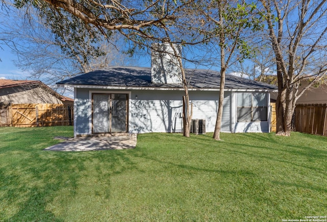 back of house with central air condition unit and a yard