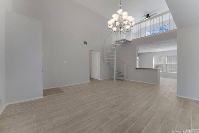 unfurnished living room featuring a towering ceiling and ceiling fan with notable chandelier