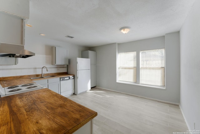 kitchen featuring a textured ceiling, white cabinetry, sink, and white appliances