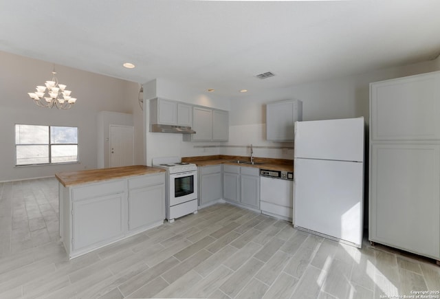 kitchen featuring white appliances, sink, a notable chandelier, hanging light fixtures, and butcher block counters