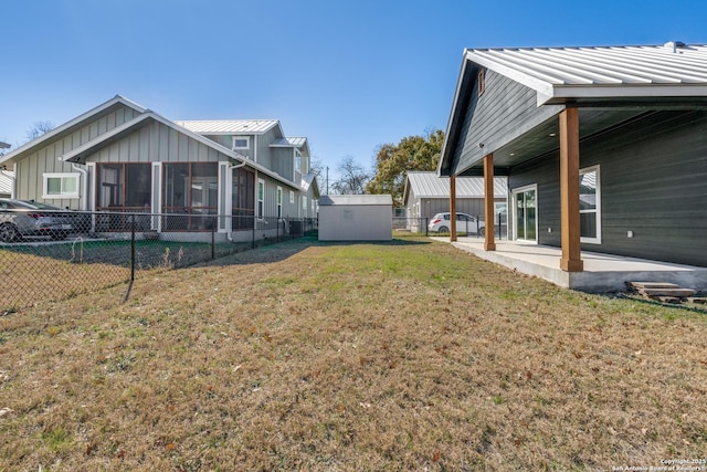 view of yard with a sunroom, a storage shed, and a patio