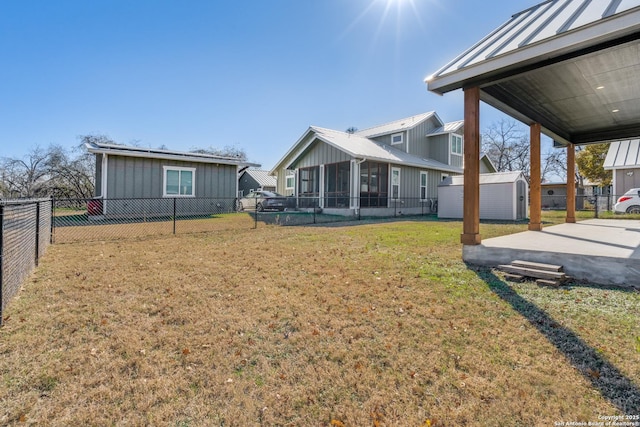 view of yard featuring a patio area, a sunroom, and a shed