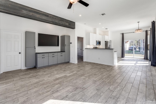 unfurnished living room featuring ceiling fan with notable chandelier