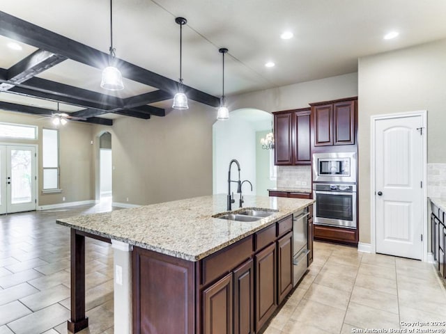 kitchen featuring stainless steel appliances, sink, pendant lighting, a center island with sink, and beamed ceiling