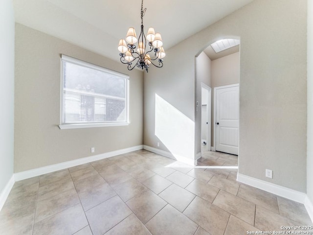 tiled empty room with an inviting chandelier