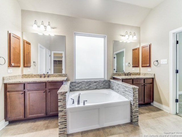 bathroom with a bath, vanity, vaulted ceiling, and tile patterned floors