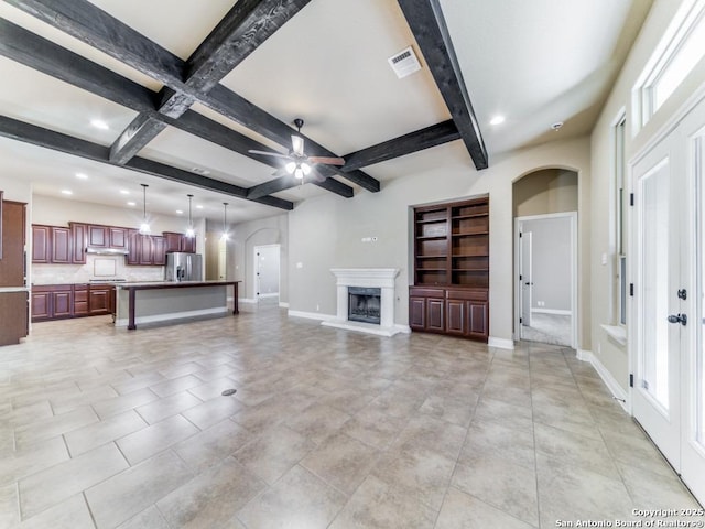 unfurnished living room with ceiling fan and beam ceiling