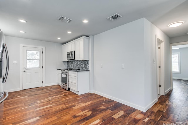 kitchen with backsplash, a wealth of natural light, white cabinets, and stainless steel appliances