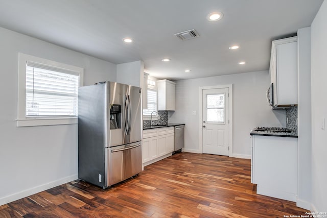 kitchen with sink, dark wood-type flooring, decorative backsplash, white cabinets, and appliances with stainless steel finishes