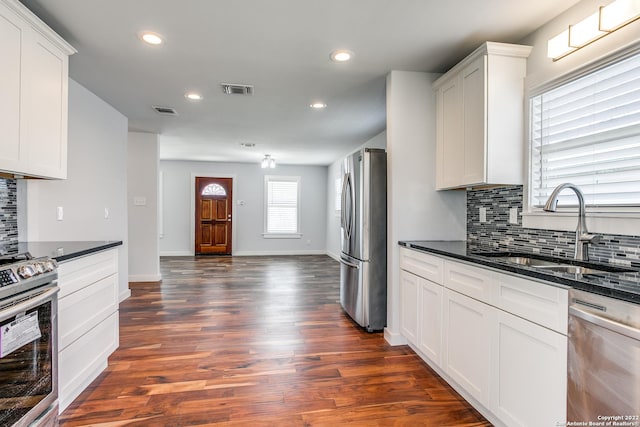 kitchen featuring appliances with stainless steel finishes, dark hardwood / wood-style flooring, backsplash, sink, and white cabinets