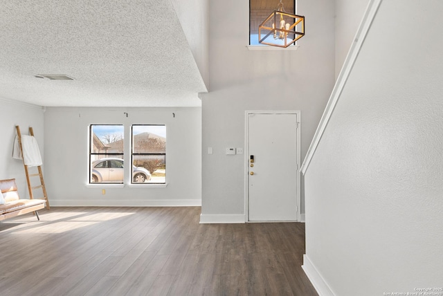 foyer entrance featuring hardwood / wood-style floors, a textured ceiling, and a notable chandelier