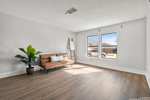 living area with wood-type flooring, a textured ceiling, and ornamental molding