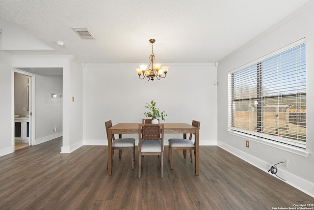 dining room with crown molding, dark hardwood / wood-style flooring, a textured ceiling, and an inviting chandelier