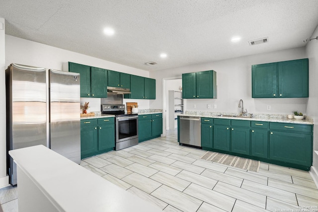 kitchen featuring a textured ceiling, stainless steel appliances, green cabinetry, and sink