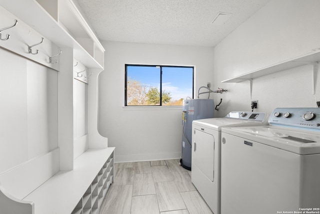 laundry room featuring washing machine and clothes dryer, water heater, and a textured ceiling