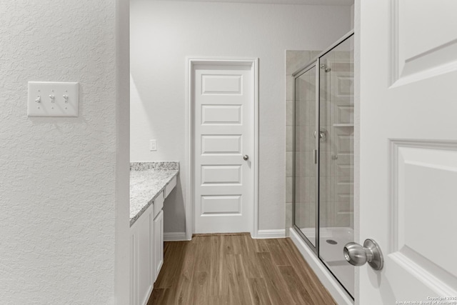 bathroom featuring a shower with shower door, wood-type flooring, and vanity