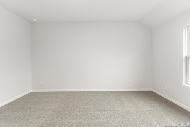 carpeted spare room with lofted ceiling