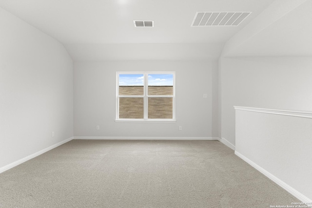 carpeted spare room featuring vaulted ceiling