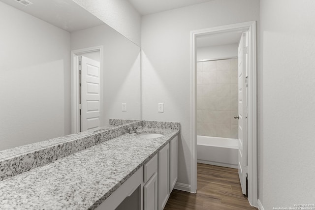 bathroom with vanity, wood-type flooring, and tiled shower / bath combo