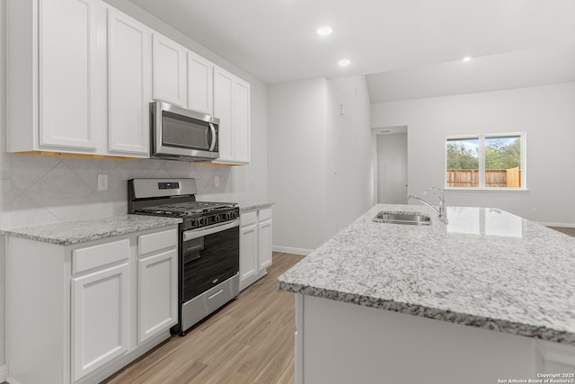 kitchen with an island with sink, sink, white cabinets, and stainless steel appliances