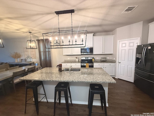 kitchen featuring sink, stainless steel appliances, a kitchen breakfast bar, pendant lighting, and a center island with sink