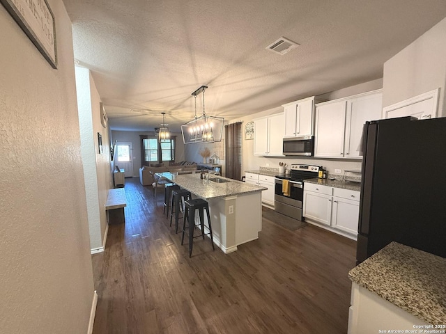 kitchen with a kitchen bar, white cabinets, an island with sink, and appliances with stainless steel finishes