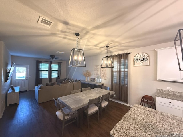 dining room with a textured ceiling, ceiling fan with notable chandelier, and dark hardwood / wood-style floors