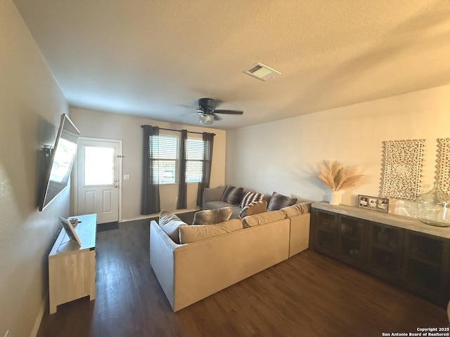 living room featuring ceiling fan, dark hardwood / wood-style flooring, and a textured ceiling