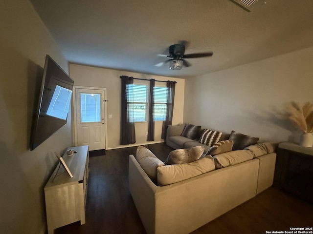 living room featuring ceiling fan and dark wood-type flooring