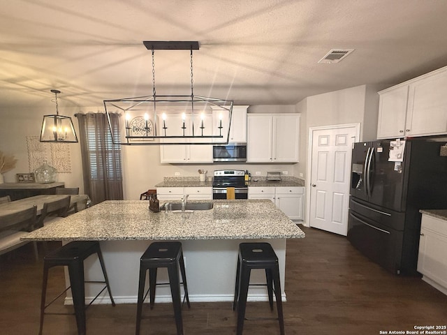 kitchen with a kitchen bar, pendant lighting, stainless steel appliances, and a kitchen island with sink