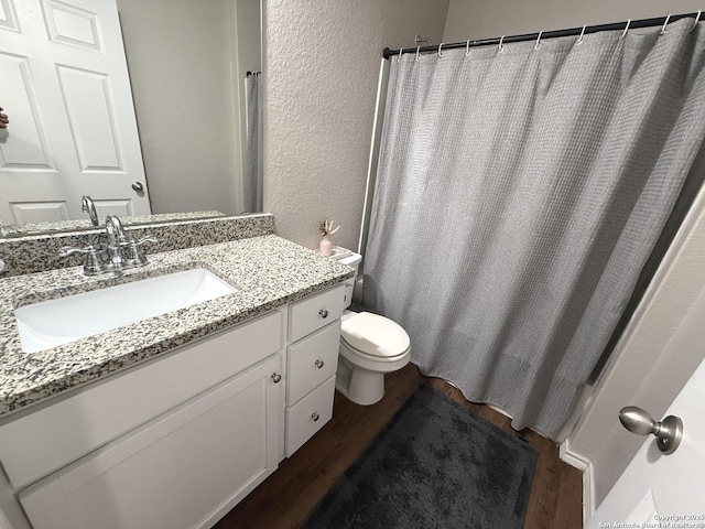 bathroom featuring toilet, vanity, and hardwood / wood-style flooring