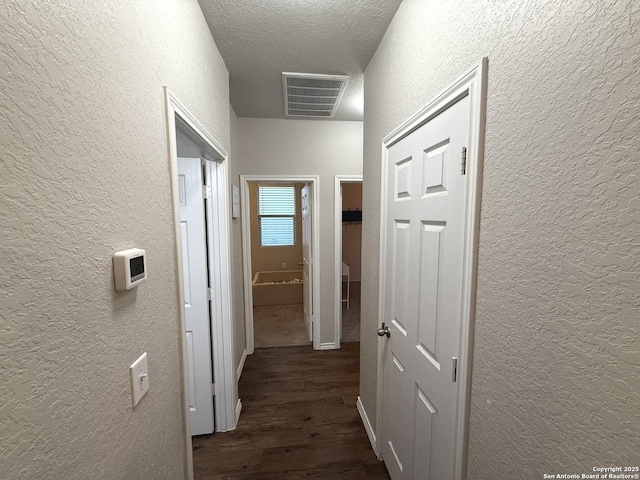 corridor featuring a textured ceiling and dark hardwood / wood-style floors