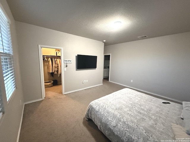 carpeted bedroom featuring a spacious closet, a closet, and a textured ceiling