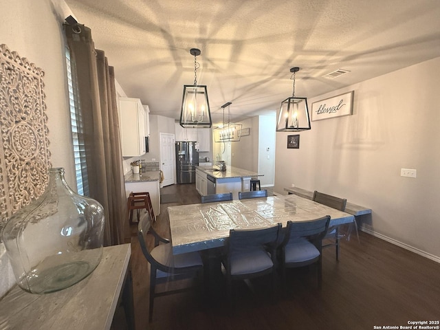 dining area featuring a textured ceiling, dark hardwood / wood-style flooring, a notable chandelier, and sink