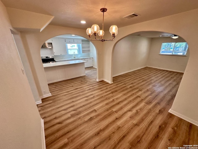 unfurnished dining area featuring sink, hardwood / wood-style floors, and ceiling fan with notable chandelier