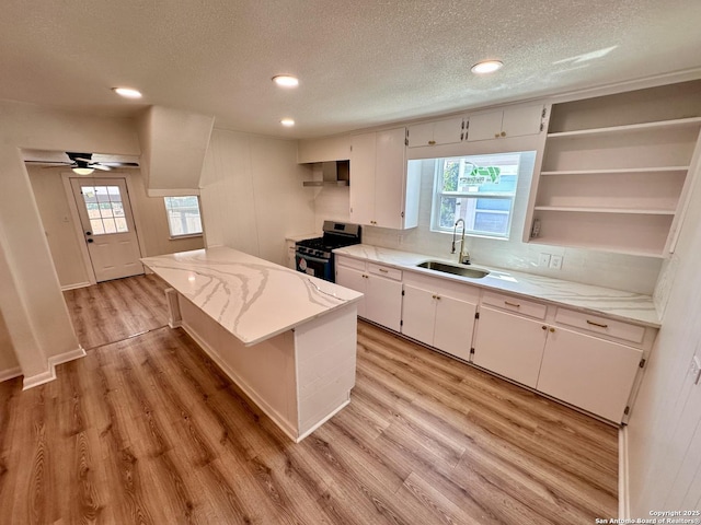 kitchen featuring sink, stainless steel gas stove, ceiling fan, a textured ceiling, and white cabinetry