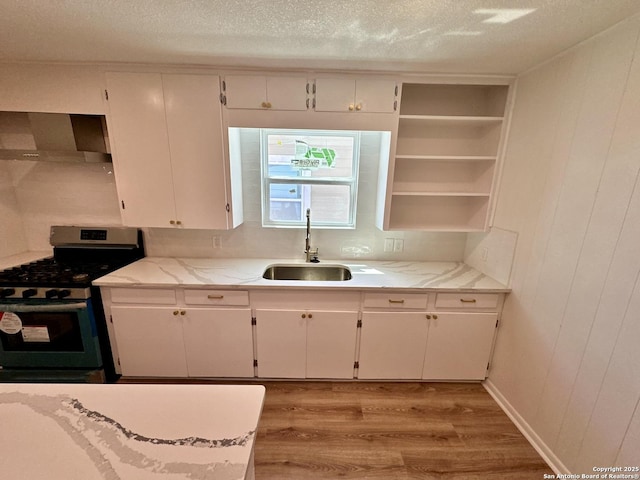 kitchen featuring sink, stainless steel gas range, a textured ceiling, white cabinets, and light wood-type flooring